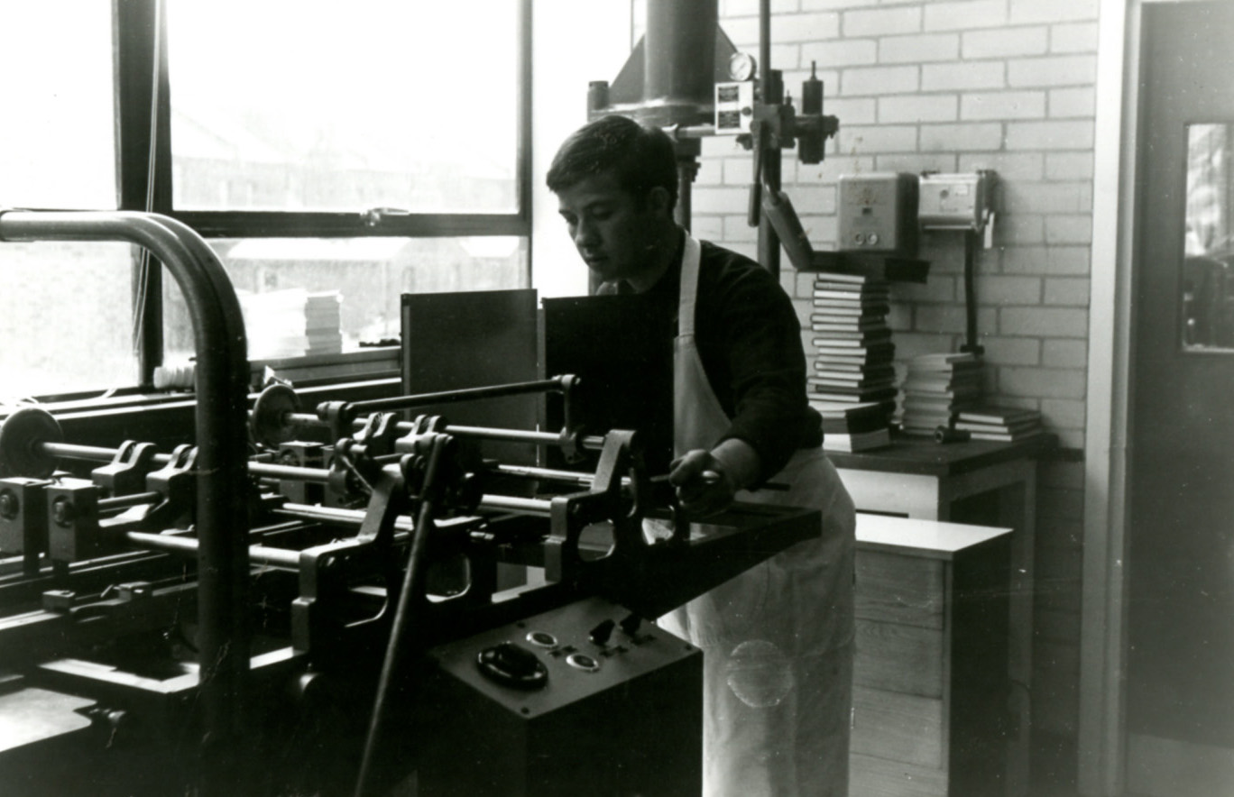 Black and white photograph of male student at printing machine